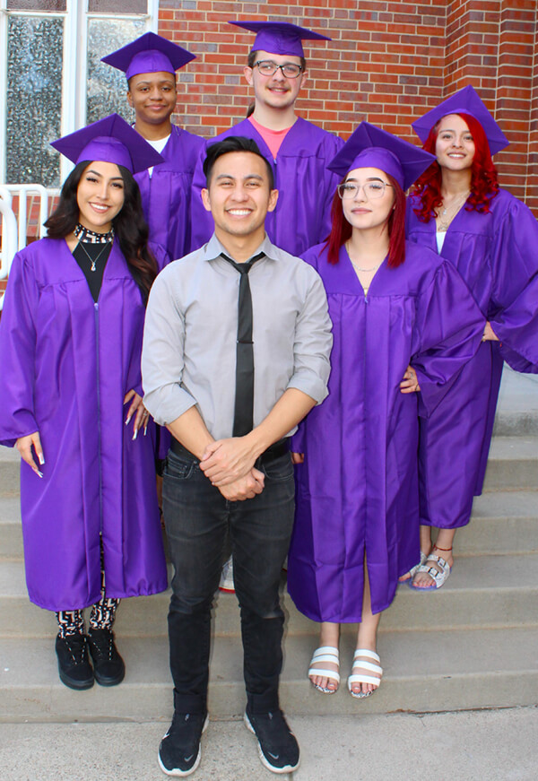high school students and school teacher on graduation day wearinn purple graduation cap and gown - Denver Street School